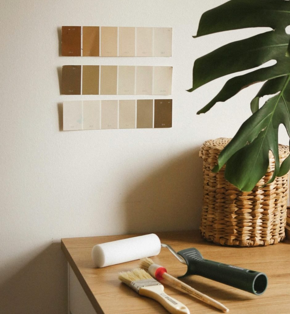 A cozy room with paint swatches, brushes, and a monstera plant in a basket.