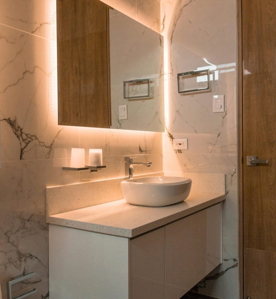 Elegant bathroom showcasing a contemporary sink, illuminated mirror, and marble tiles for a luxurious interior.