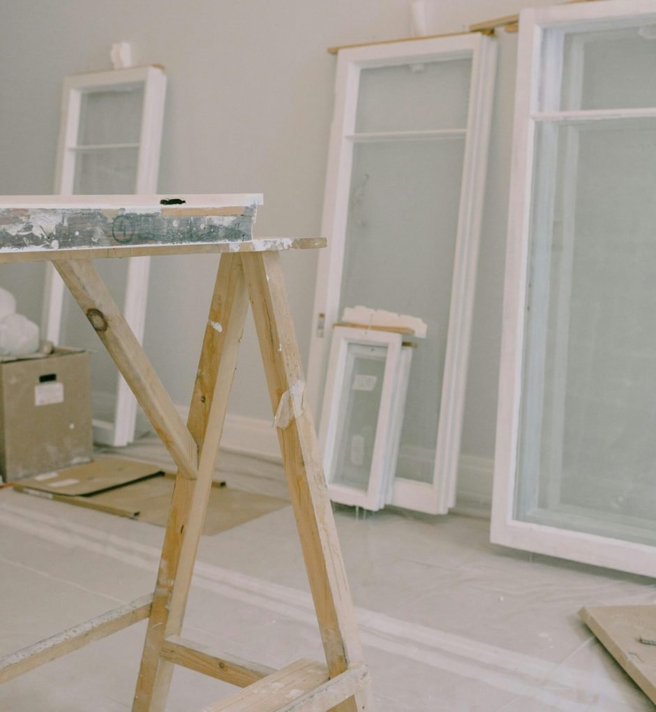 Interior of room with wooden workbench and windows removed from hinges with white frame placed near wall in light room during repair works