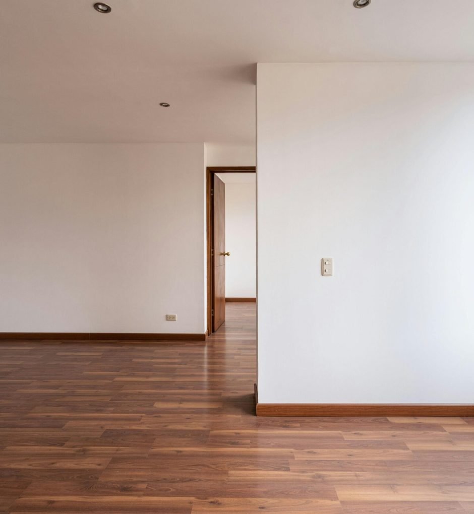 Empty room with wooden floors and white walls, ideal for real estate or interior design concepts.